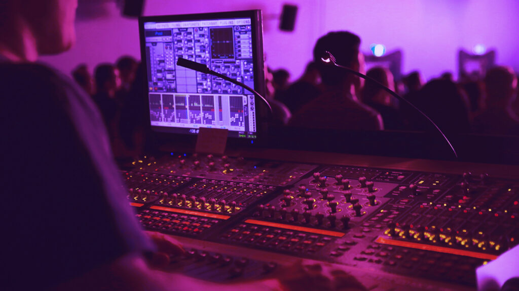 Pink hue image of a man behind a mixing desk